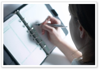 A close-up of a person writing in a planning book.